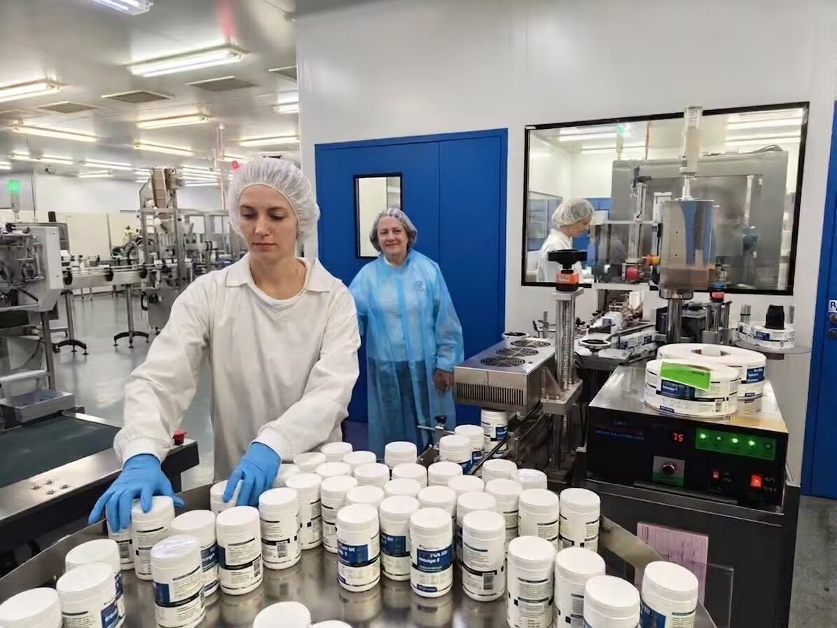 Operators labelling bottles in a cleanroom